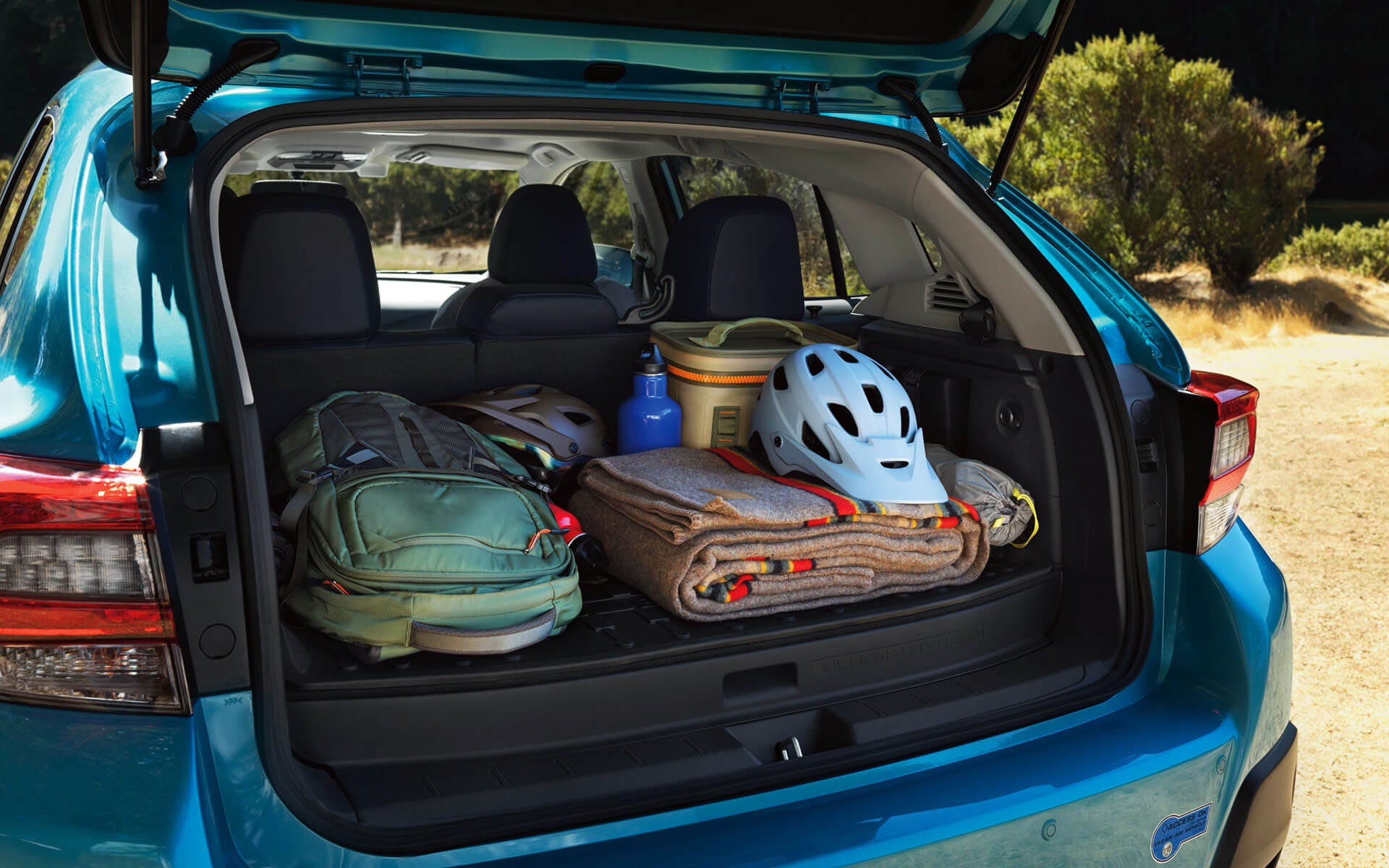 A backpack, blanket, and bike helmet in the rear cargo area of a Crosstrek Hybrid | Sunset Hills Subaru in Sunset Hills MO