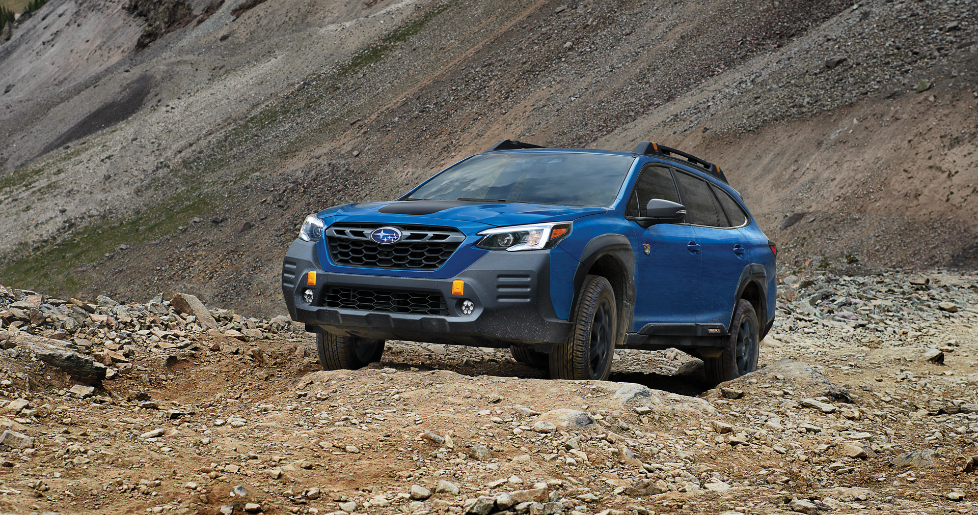 A 2023 Outback Wilderness driving on a trail in the mountains. | Sunset Hills Subaru in Sunset Hills MO